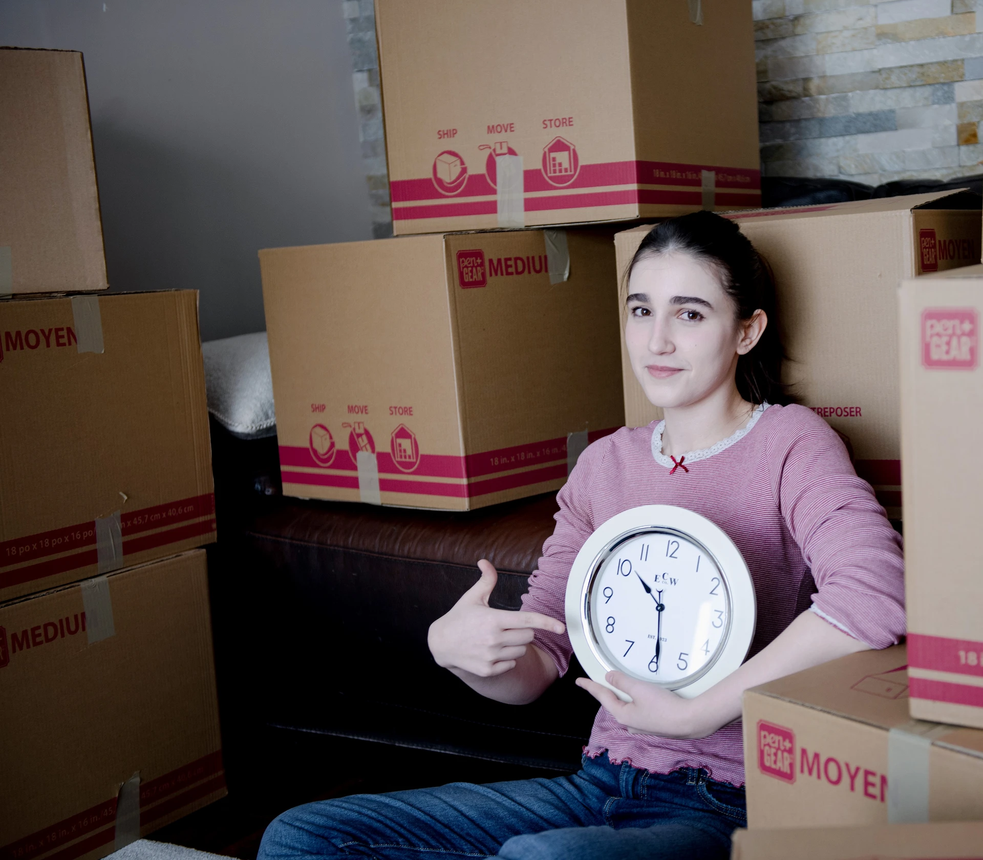 Customer holding a clock beside moving boxes to represent on-time moving services