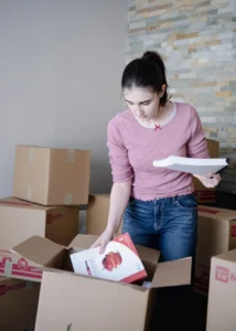 Woman packing household items into moving boxes before relocation