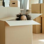 Child playing inside a cardboard moving box during a family move