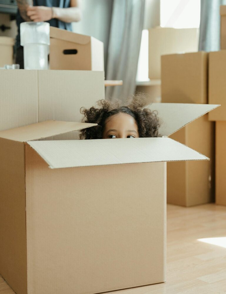 Child playing inside a cardboard moving box during a family move